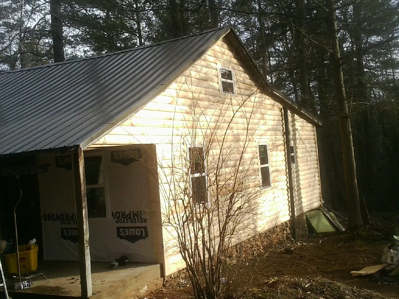 Log siding gable end under a dark metal roof edge in Wakefield