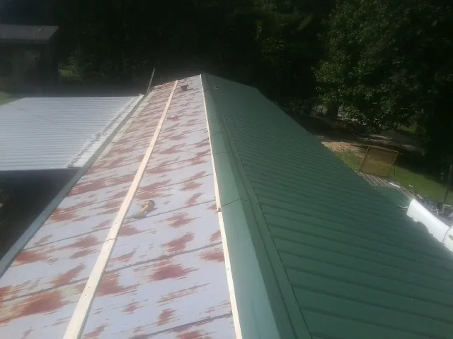 Old rusted panels beside newly installed green metal roofing — Wind Damage Roof Repair by Roofing Brothers in Wakefield